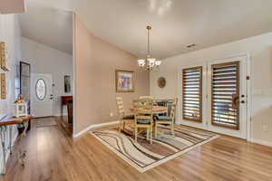 Dining room with vaulted ceiling, plenty of natural light, and light wood-type flooring