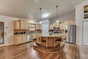 Kitchen featuring stainless steel appliances, tasteful backsplash, a kitchen island, and vaulted ceiling