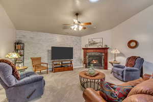 Carpeted living room featuring ceiling fan, a fireplace, and vaulted ceiling