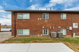 Rear view of house featuring central AC unit and a yard