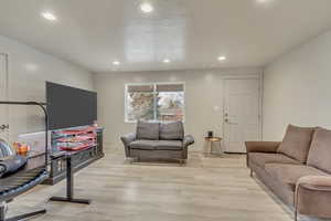 Living room with a textured ceiling and light hardwood / wood-style floors