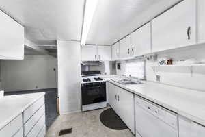 Kitchen featuring dishwasher, sink, white cabinetry, a textured ceiling, and range with gas stovetop