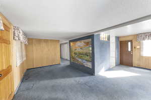 Unfurnished room featuring dark colored carpet and wooden walls