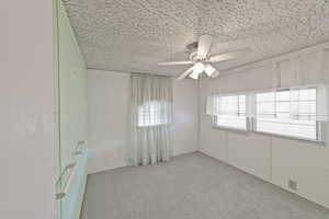 Empty room with ceiling fan and light carpet