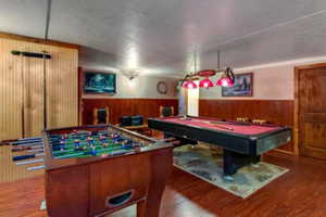 Game room featuring wood-type flooring, pool table, and wood walls