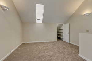 Additional living space with lofted ceiling and light colored carpet