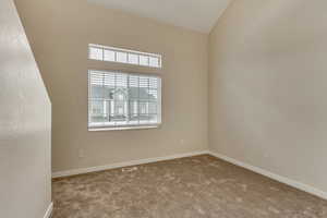 Unfurnished room with vaulted ceiling and light colored carpet