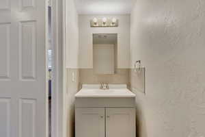 Bathroom featuring vanity, a textured ceiling, and backsplash