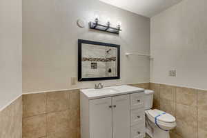 Bathroom with tile walls, vanity, and toilet