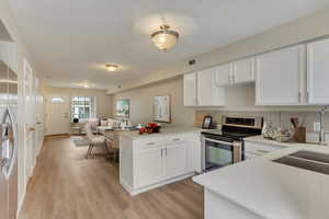 Kitchen featuring kitchen peninsula, white cabinets, and appliances with stainless steel finishes