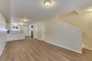 Unfurnished living room with sink, a textured ceiling, and light wood-type flooring