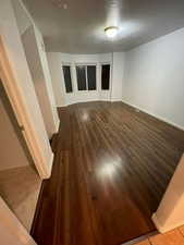 Empty room featuring dark wood-type flooring and a textured ceiling