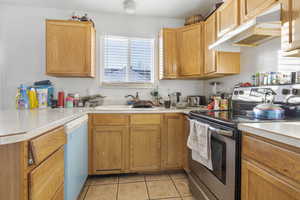 Kitchen featuring light tile patterned floors, sink, and appliances with stainless steel finishes