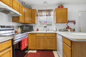 Kitchen featuring white dishwasher, light tile patterned floors, electric range, and kitchen peninsula