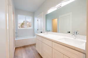 Primary Bathroom with wood-type flooring, full quarts vanity, and a quartz tub to relax in