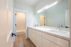 Bathroom with quarts vanity, toilet, and hardwood / wood-style floors