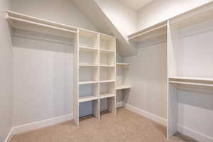 Walk in closet featuring light carpet, and spacious built ins