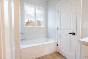 Primary Bathroom featuring a tub to relax in and wood-type flooring