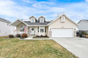 View of front of home featuring a garage, a front yard, solar panels, and a porch