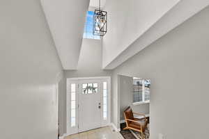 Tiled foyer with a high ceiling and a notable chandelier