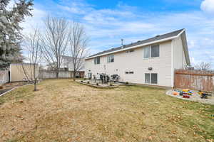 Rear view of house featuring a yard, a patio area, and a storage unit