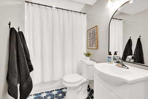 Full bathroom with shower / bathtub combination with curtain, vanity, toilet, and tile patterned floors