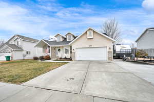 View of front of home with a garage, a front yard, solar panels, and covered porch