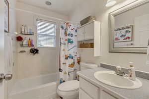 Full bathroom with vanity, shower / tub combo, and toilet