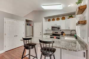 Kitchen with lofted ceiling, sink, stainless steel appliances, and kitchen peninsula