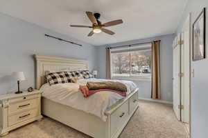 Bedroom with ceiling fan and light colored carpet