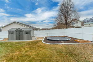 View of yard featuring a trampoline and a storage unit