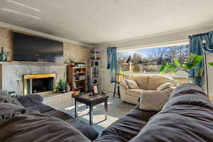 Living room with a textured ceiling, crown molding, and a fireplace