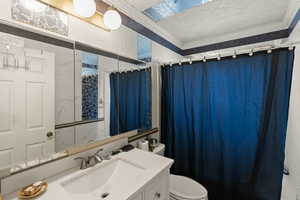 Bathroom with toilet, vanity, ornamental molding, and walk in shower