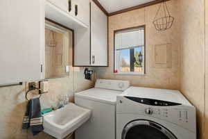 Laundry room with electric panel, sink, crown molding, separate washer and dryer, and cabinets