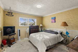 Bedroom featuring a textured ceiling and crown molding