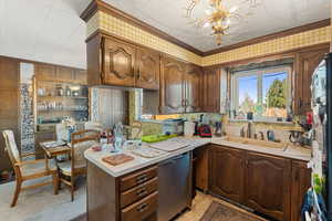 Kitchen featuring a notable chandelier, decorative light fixtures, dishwasher, crown molding, and sink