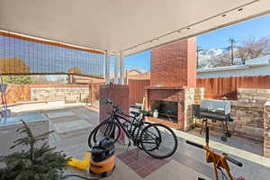 View of patio with a mountain view, a grill, and an outdoor brick fireplace