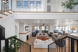 Living room with ceiling fan, light wood-type flooring, and a high ceiling