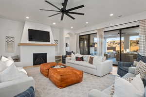 Living room featuring ceiling fan, a fireplace, and light hardwood / wood-style flooring