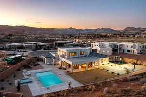 Back house at dusk featuring a mountain view and a patio