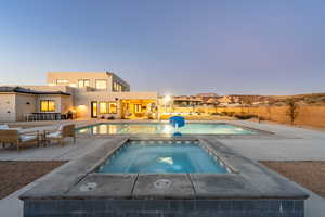 Pool at dusk with an in ground hot tub and a patio area