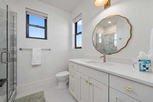 Bathroom with vanity, toilet, a shower with shower door, and tile patterned flooring