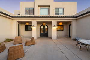 Exterior entry at dusk featuring french doors and a patio area