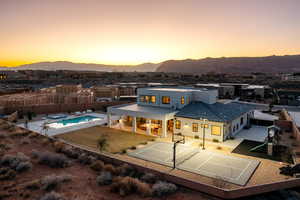 Back house at dusk with a mountain view, basketball court, and a patio area