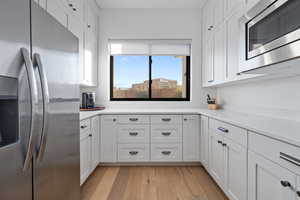 Kitchen featuring stainless steel appliances, white cabinets, and light wood-type flooring