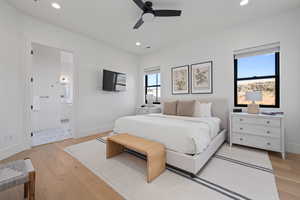 Bedroom featuring ceiling fan, ensuite bath, and light hardwood / wood-style floors