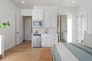 Interior space with ensuite bathroom, sink, and light wood-type flooring