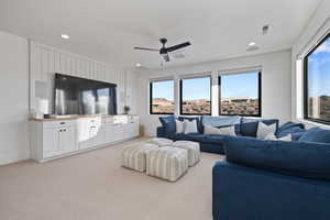 Carpeted living room with ceiling fan and plenty of natural light