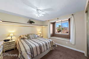 Carpeted bedroom with a textured ceiling and ceiling fan