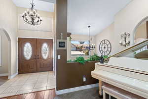 Foyer featuring light tile patterned flooring and a chandelier